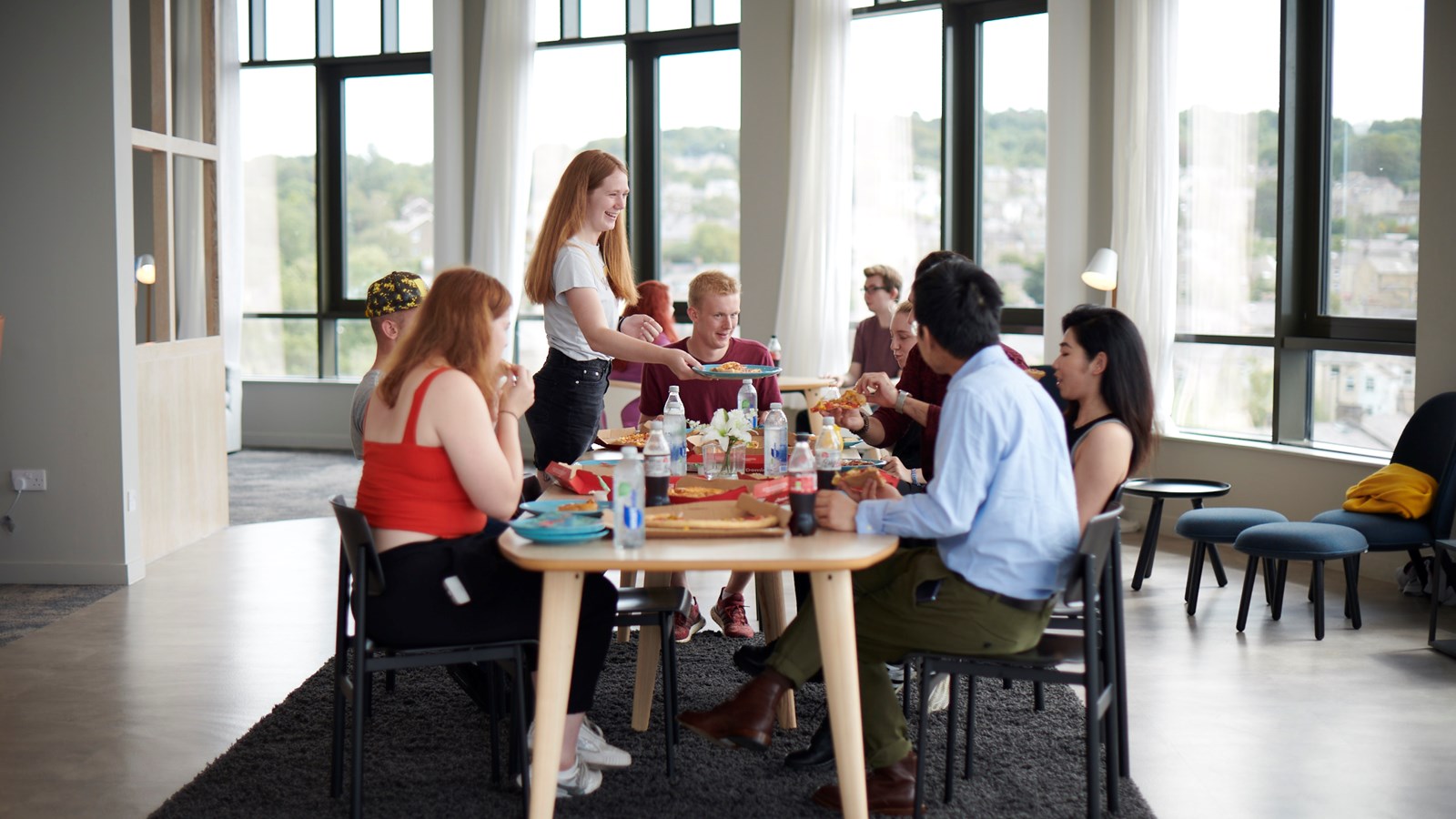 Students sitting at a table in the sky lounge eating food in Lancaster student accommodation